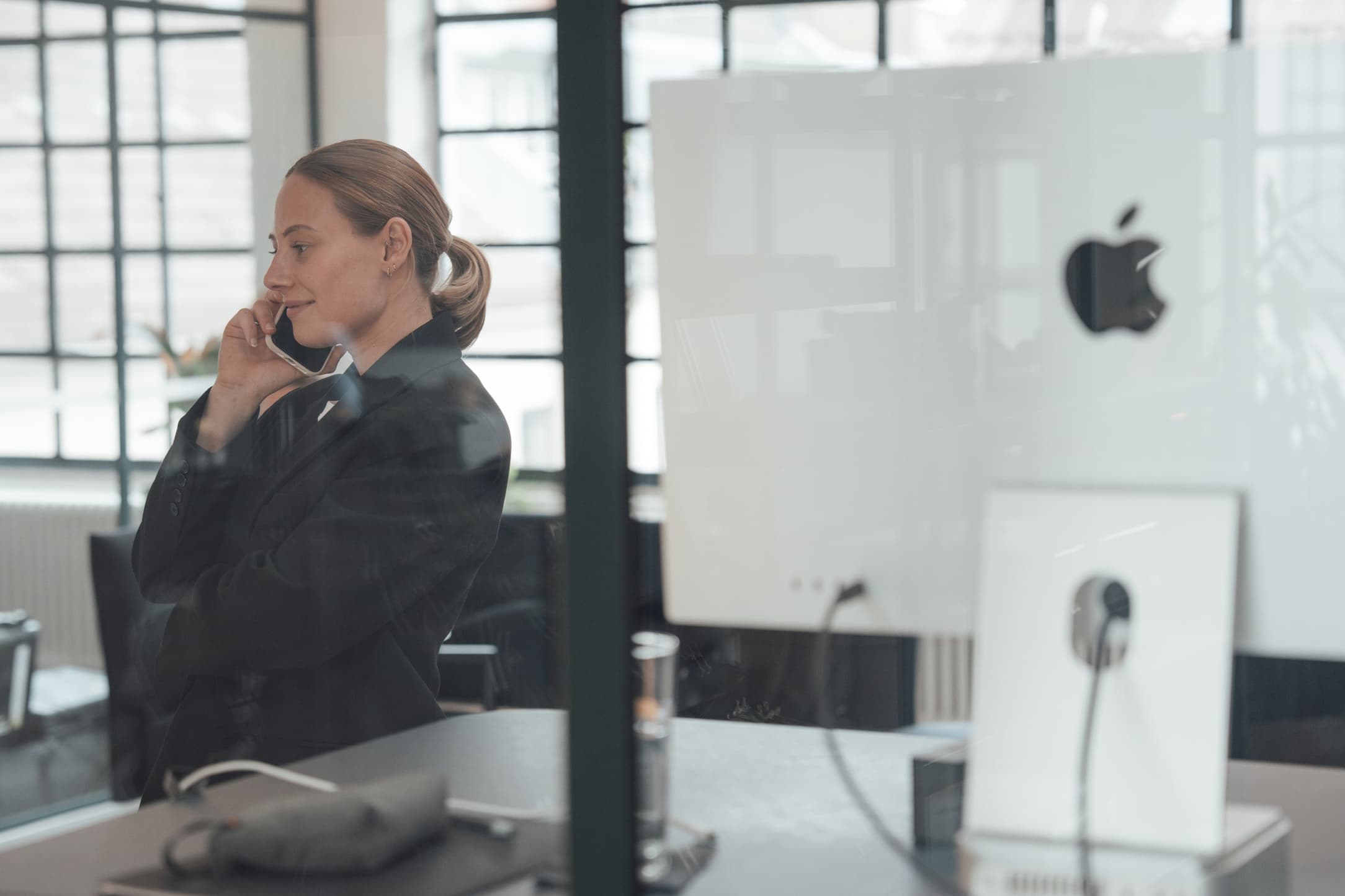 Eine Frau telefoniert an einem Schreibtisch im Büro.